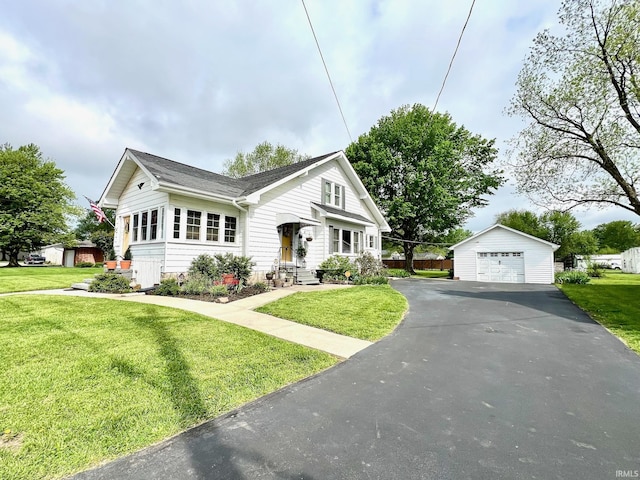 view of front facade featuring driveway, roof with shingles, a detached garage, an outdoor structure, and a front lawn
