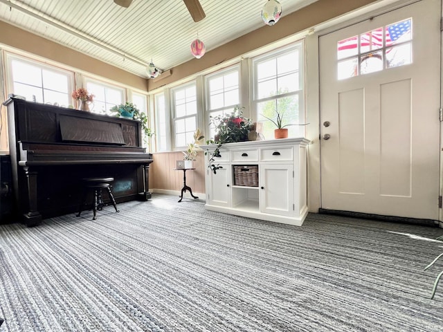 carpeted foyer featuring baseboards, plenty of natural light, and a ceiling fan