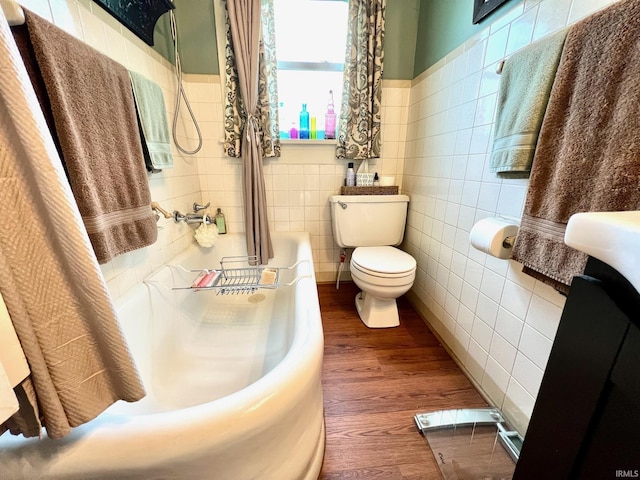 full bathroom with wood finished floors, a bath, toilet, and tile walls