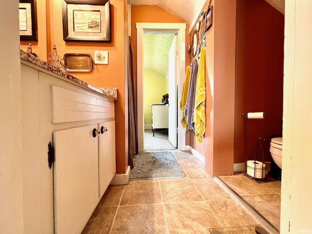 corridor featuring baseboards and vaulted ceiling