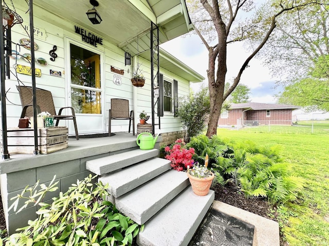view of exterior entry featuring a porch and a lawn