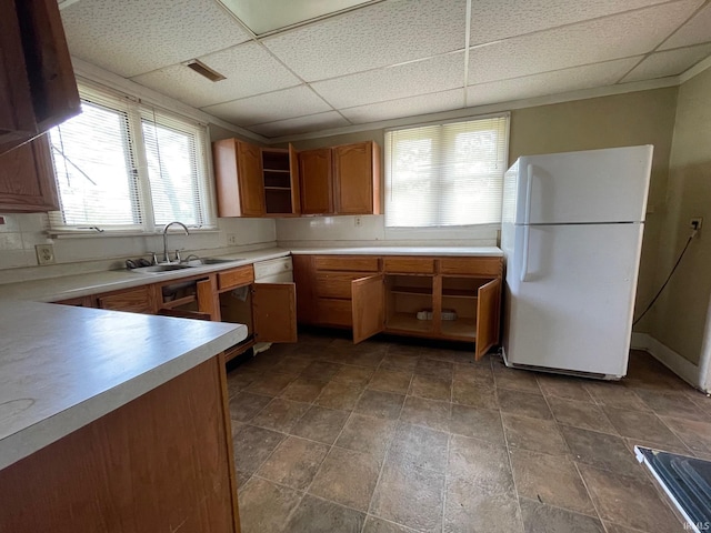kitchen with brown cabinetry, open shelves, a sink, light countertops, and freestanding refrigerator