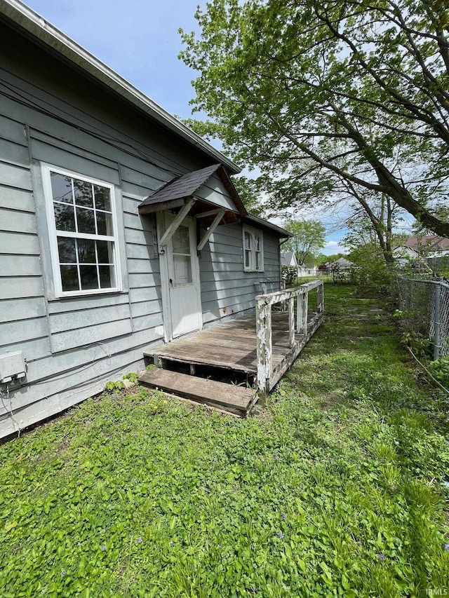 doorway to property featuring fence, a wooden deck, and a yard