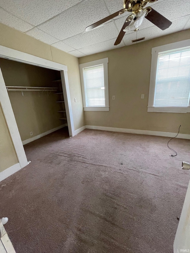 unfurnished bedroom with carpet floors, baseboards, a paneled ceiling, and a closet