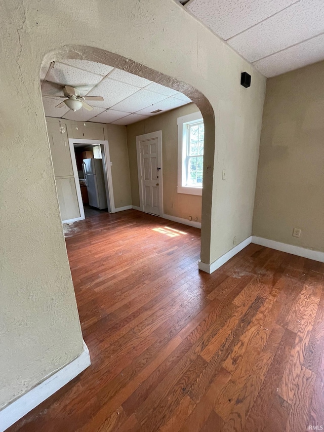 interior space with arched walkways, baseboards, a ceiling fan, and wood finished floors
