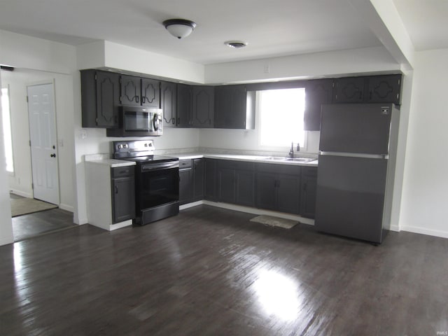 kitchen with light countertops, a sink, dark wood-type flooring, and stainless steel appliances