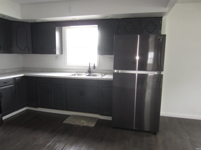 kitchen featuring freestanding refrigerator, a sink, dark wood finished floors, and light countertops