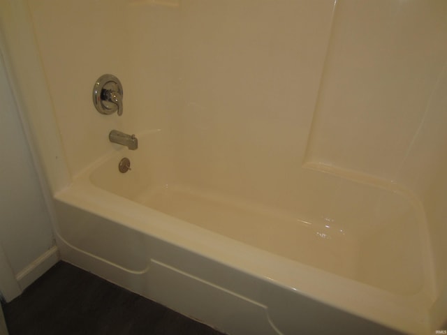 bathroom featuring baseboards, bathtub / shower combination, and wood finished floors
