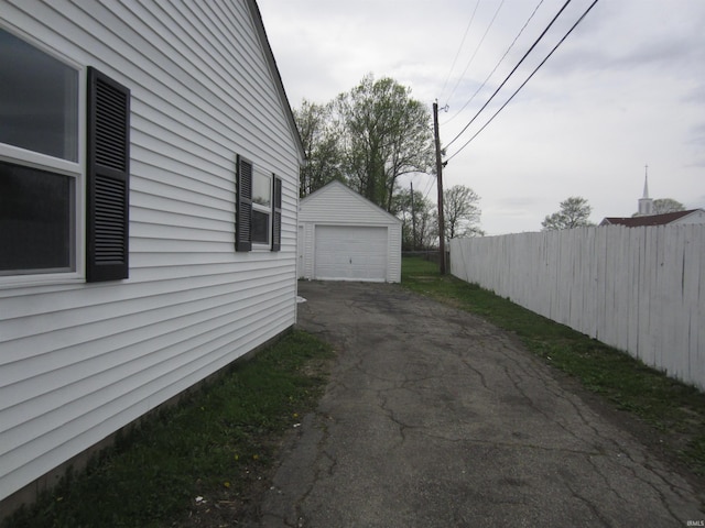 view of home's exterior with an outdoor structure, a garage, aphalt driveway, and fence