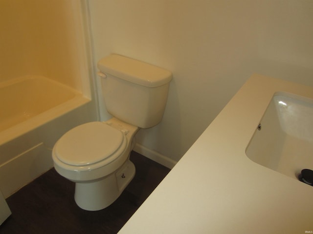 bathroom featuring toilet, baseboards, a sink, and a bath