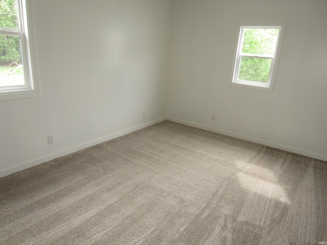 empty room featuring baseboards and light colored carpet