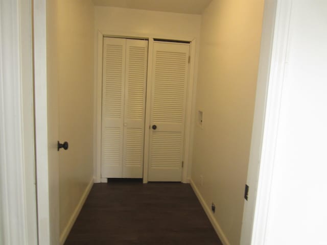 corridor with dark wood-style flooring and baseboards