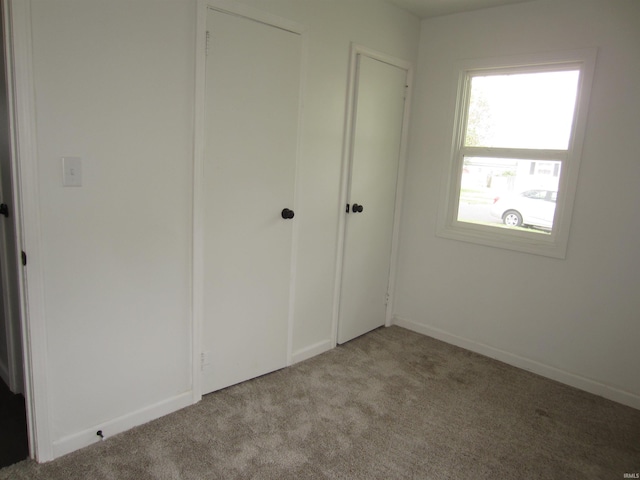 unfurnished bedroom featuring carpet floors, baseboards, and a closet
