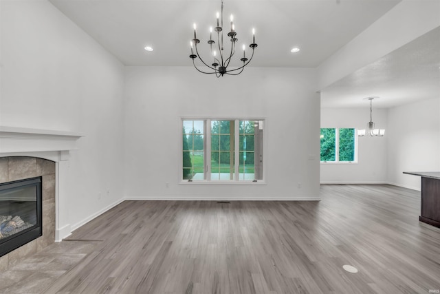 unfurnished living room with baseboards, a notable chandelier, wood finished floors, and a fireplace