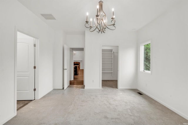 interior space featuring carpet floors, baseboards, visible vents, and an inviting chandelier