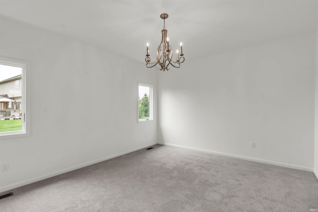 unfurnished room featuring baseboards, carpet flooring, and a notable chandelier