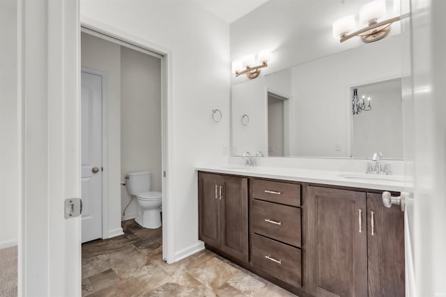 full bathroom with a sink, baseboards, toilet, and double vanity