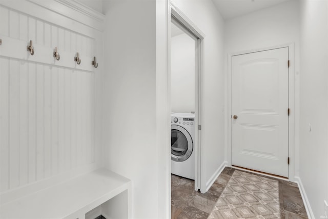 clothes washing area featuring washer / clothes dryer, baseboards, and stone finish floor