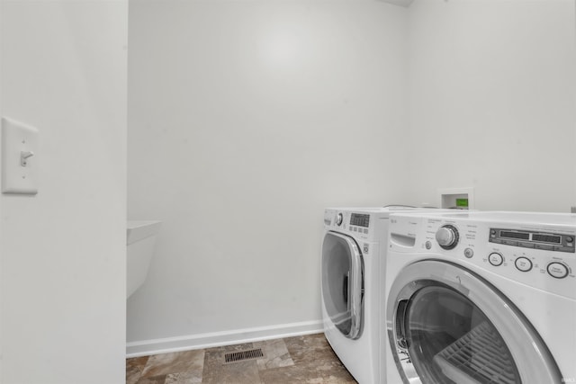washroom with laundry area, baseboards, washer and dryer, and visible vents