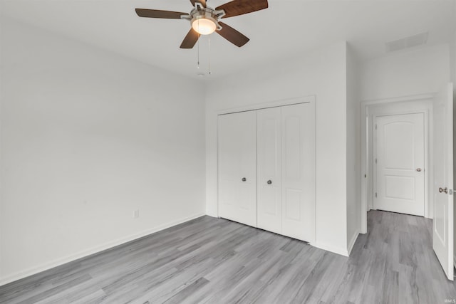 unfurnished bedroom featuring visible vents, baseboards, wood finished floors, and a closet