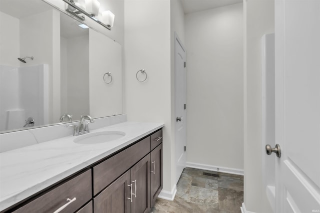 bathroom with vanity, visible vents, baseboards, walk in shower, and stone finish floor