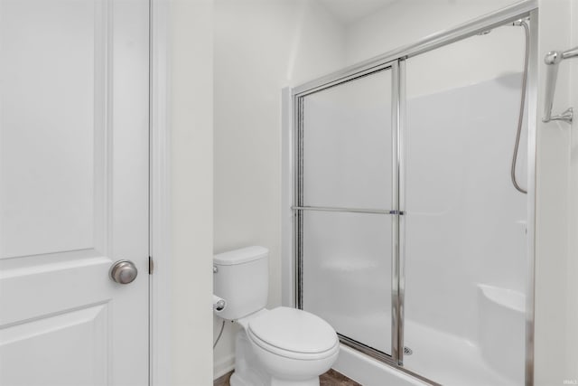 bathroom featuring toilet and a shower stall