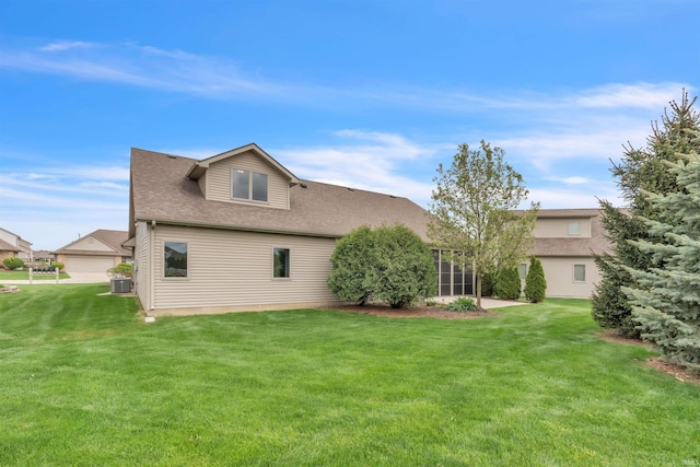 back of property featuring roof with shingles, a yard, and central AC