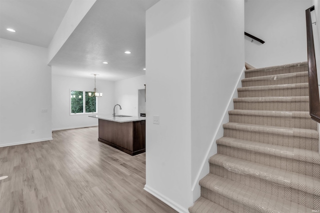 stairs with recessed lighting, baseboards, an inviting chandelier, and wood finished floors