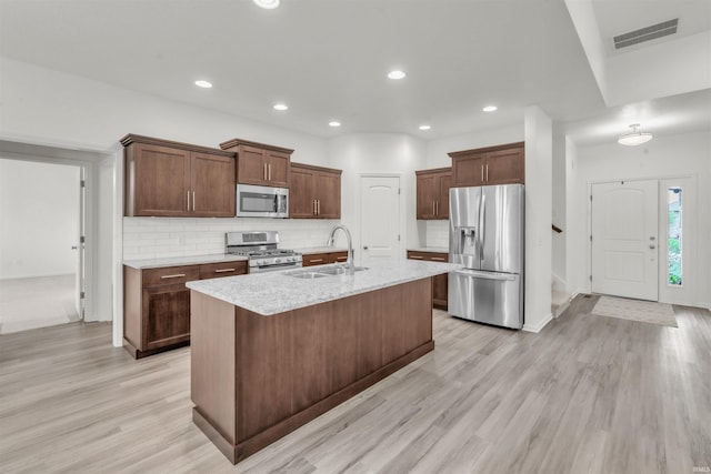kitchen with a sink, an island with sink, stainless steel appliances, tasteful backsplash, and visible vents