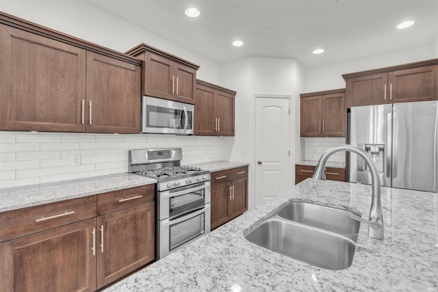 kitchen featuring light stone countertops, recessed lighting, a sink, appliances with stainless steel finishes, and backsplash