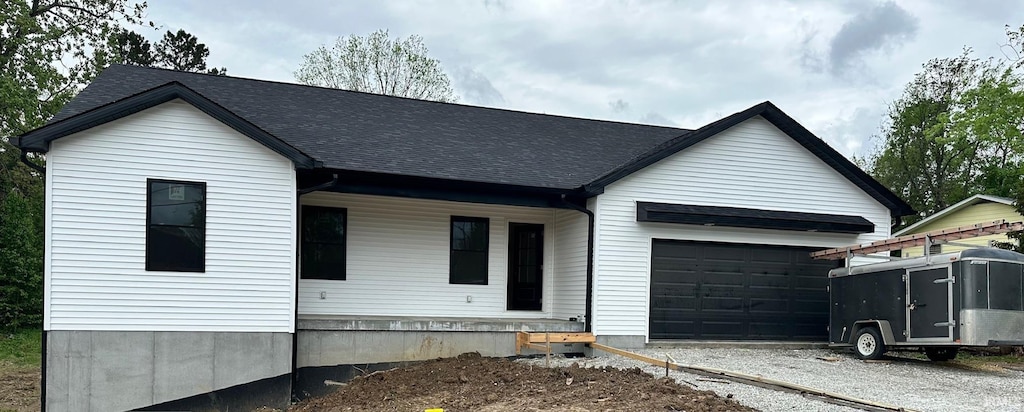 view of front of house featuring a garage, gravel driveway, and a shingled roof