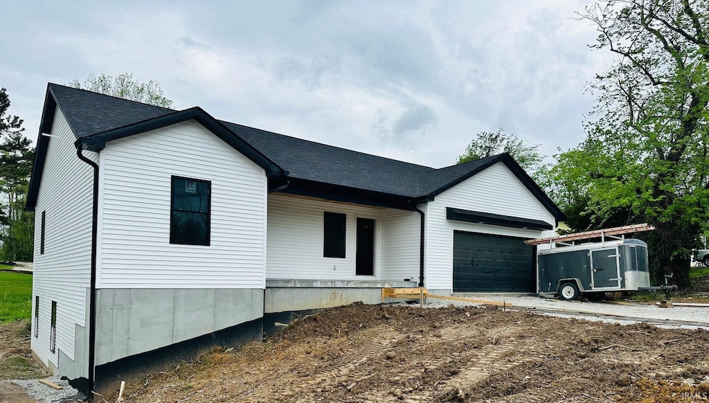 view of front of home featuring an attached garage and a shingled roof