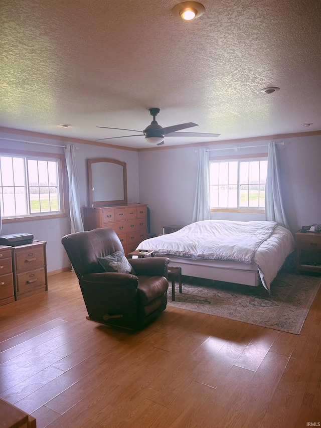 bedroom with light wood-style flooring, a textured ceiling, and multiple windows