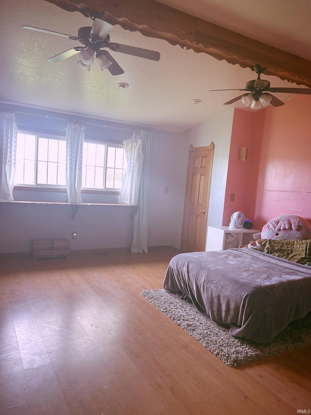 bedroom featuring ceiling fan, lofted ceiling with beams, and wood finished floors
