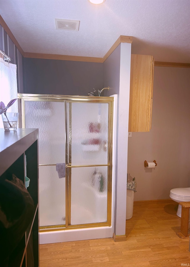 full bath featuring toilet, visible vents, wood finished floors, and a stall shower