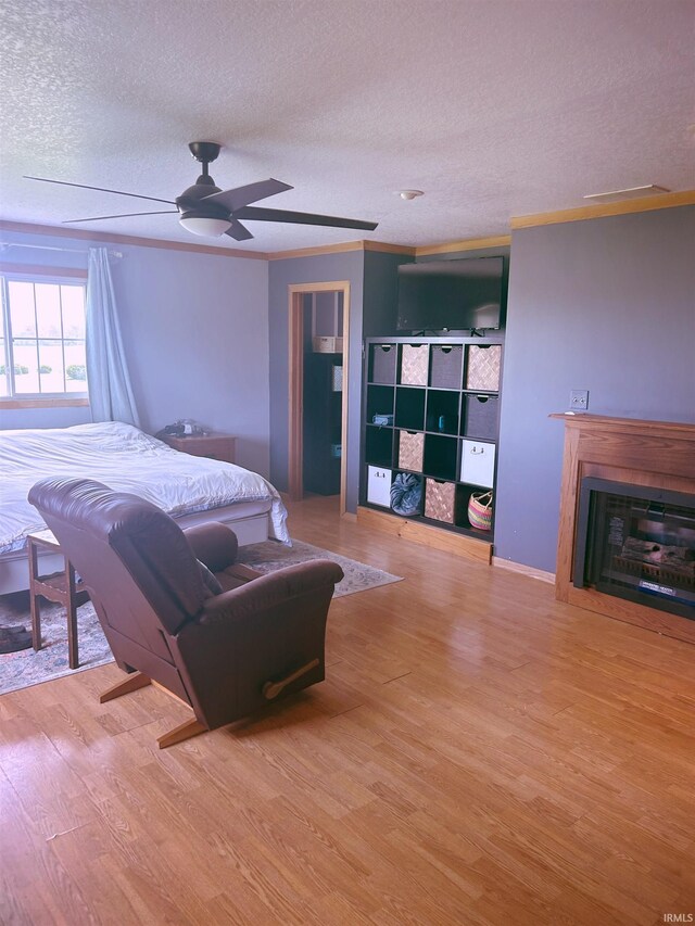 bedroom featuring a ceiling fan, a textured ceiling, wood finished floors, and a fireplace