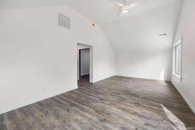 empty room with baseboards, vaulted ceiling, dark wood finished floors, and visible vents
