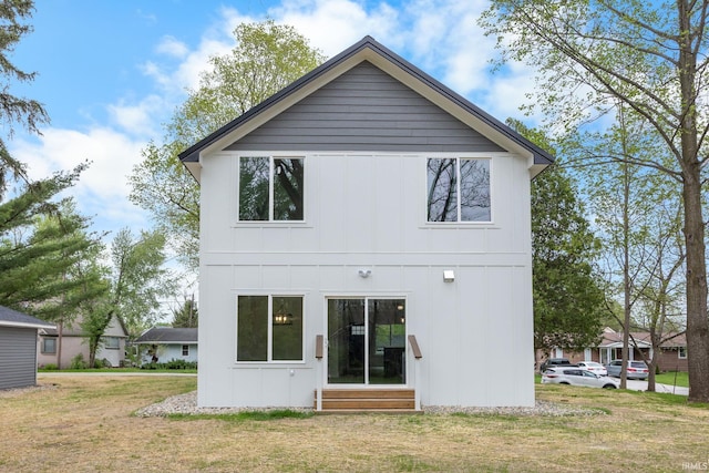 back of property with entry steps, board and batten siding, and a yard