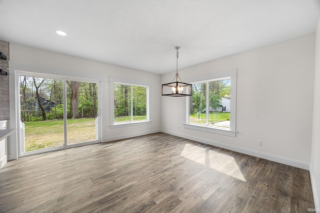 unfurnished dining area with baseboards, a chandelier, and a wealth of natural light