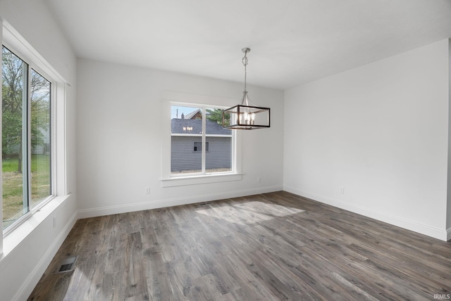 unfurnished dining area with an inviting chandelier, baseboards, wood finished floors, and visible vents