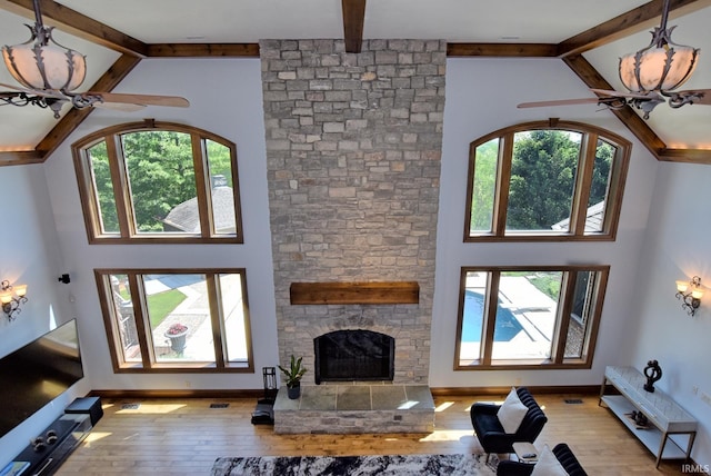 2200 Speaker Rd, Evansville, IN 47712 - living area featuring high vaulted ceiling, wood-type flooring, beamed ceiling, a stone fireplace, and baseboards