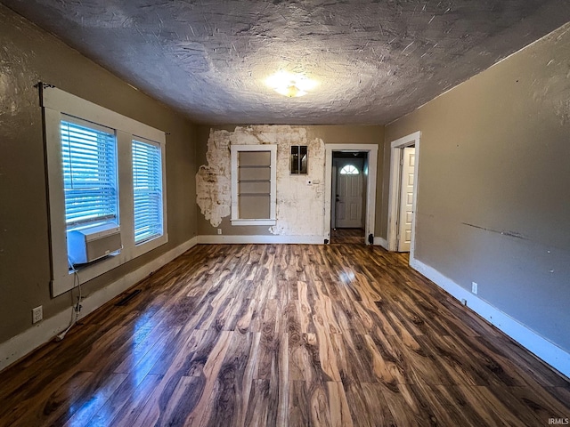 interior space featuring baseboards, a textured ceiling, wood finished floors, and cooling unit