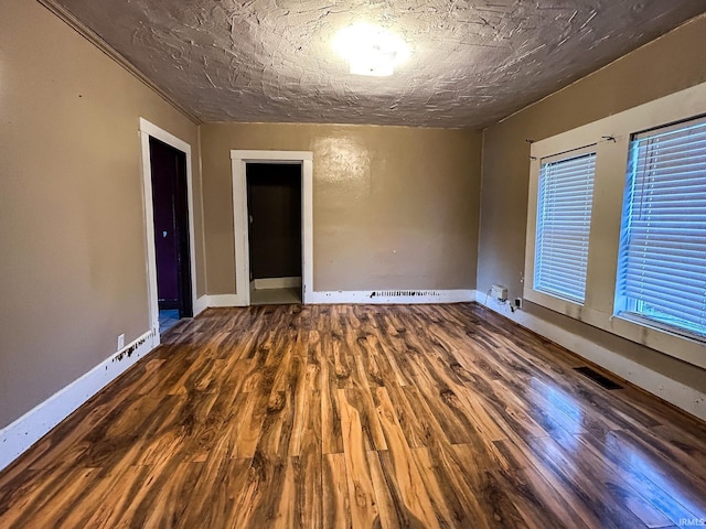 unfurnished room featuring baseboards, wood finished floors, and visible vents