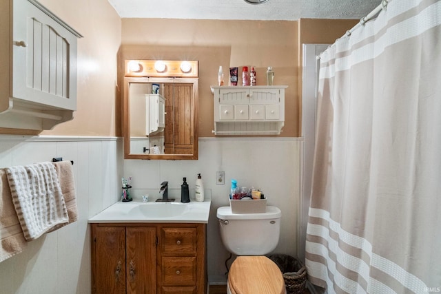 bathroom with a shower with curtain, vanity, wainscoting, and toilet