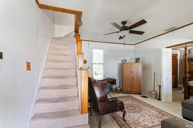 stairway with crown molding, carpet floors, a ceiling fan, and visible vents