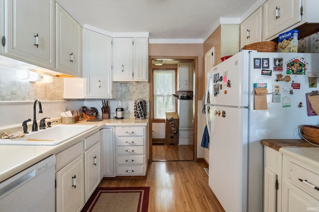kitchen with white appliances, light countertops, white cabinets, a sink, and light wood finished floors