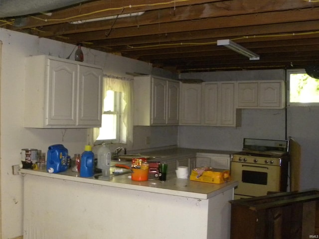 8207 Lehman Rd, Worthington, IN 47471 - kitchen featuring white gas range oven, a peninsula, white cabinets, a sink, and light countertops