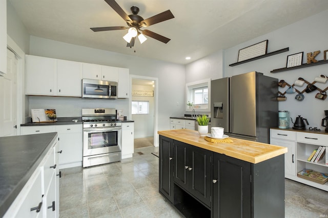 kitchen featuring dark cabinetry, wood counters, white cabinetry, and stainless steel appliances