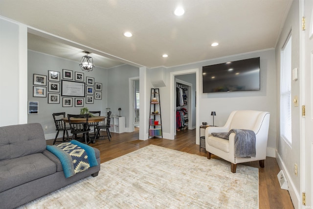 living room with crown molding, baseboards, recessed lighting, and wood finished floors