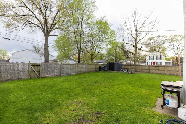 view of yard with an outdoor structure, a fenced backyard, and a storage shed